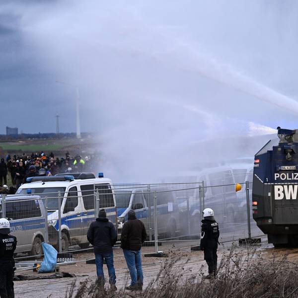Die Polizei fährt mit einem Wasserwerfer bei einer Demonstration an Klimaaktivisten vorbei.