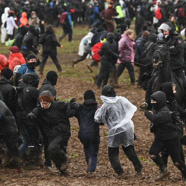 Berittene Polizisten drängen Demonstrierende von der Tagebaukante weg.