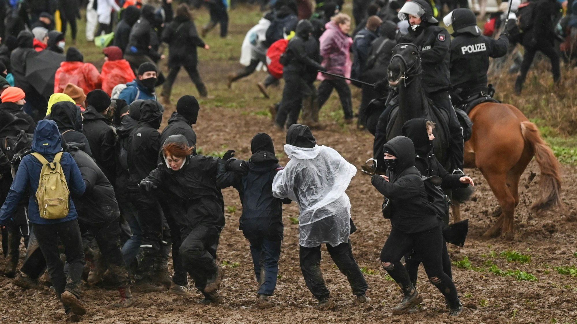 Berittene Polizisten drängen Demonstrierende von der Tagebaukante weg.