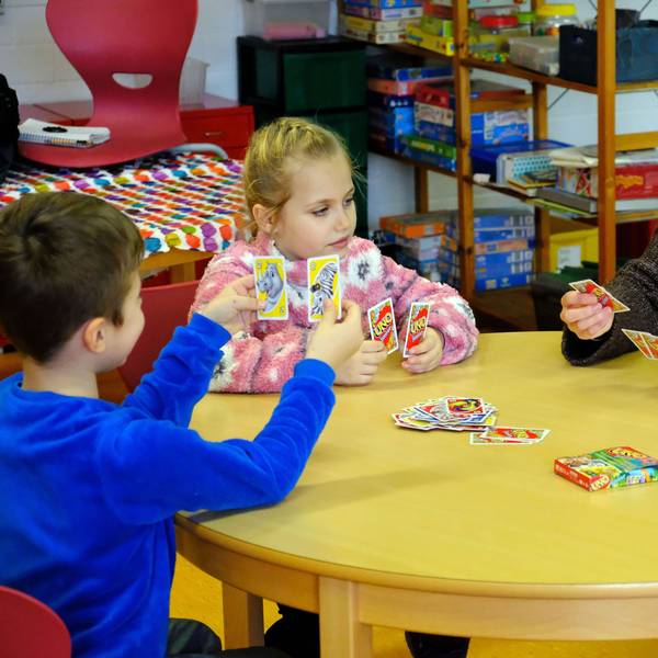 Sprachpatin Elisa Schmitz und ihre beiden Schützlinge aus der Grundschule in Hellenthal-Reifferscheid spielen eine Partie UNO.