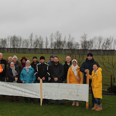19 Anwohner haben sich mit einem Protestbanner vor der Fläche postiert, auf der ein Teil des Dahlemer Solarparks geplant ist. Auf dem Banner steht: „Wir wollen hier keinen Solarpark.“