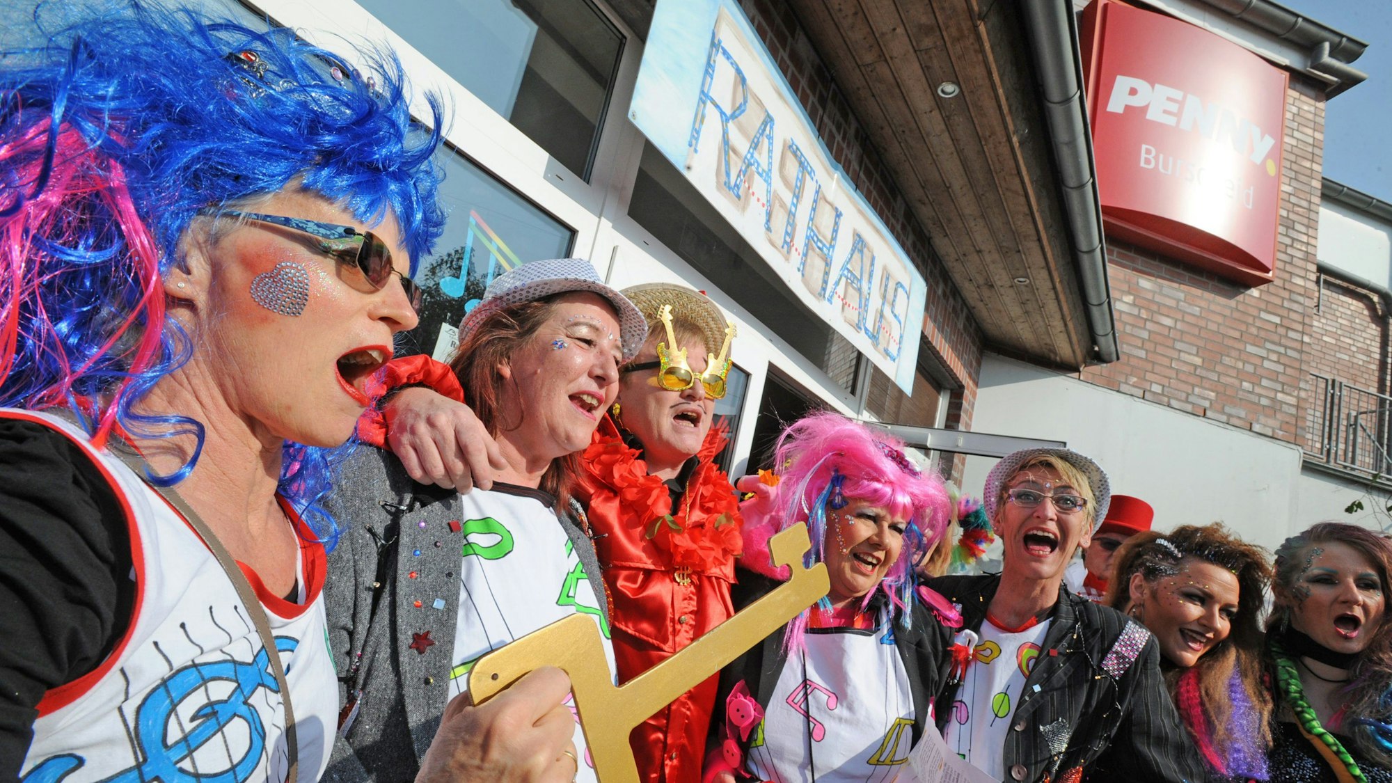 Verkleidete Frauen singen Arm in Arm mit dem 2021 verstorbenen Bürgermeister Stefan Caplan. Eine von ihnen hält einen symbolischen Stadtschlüssel in der Hand.