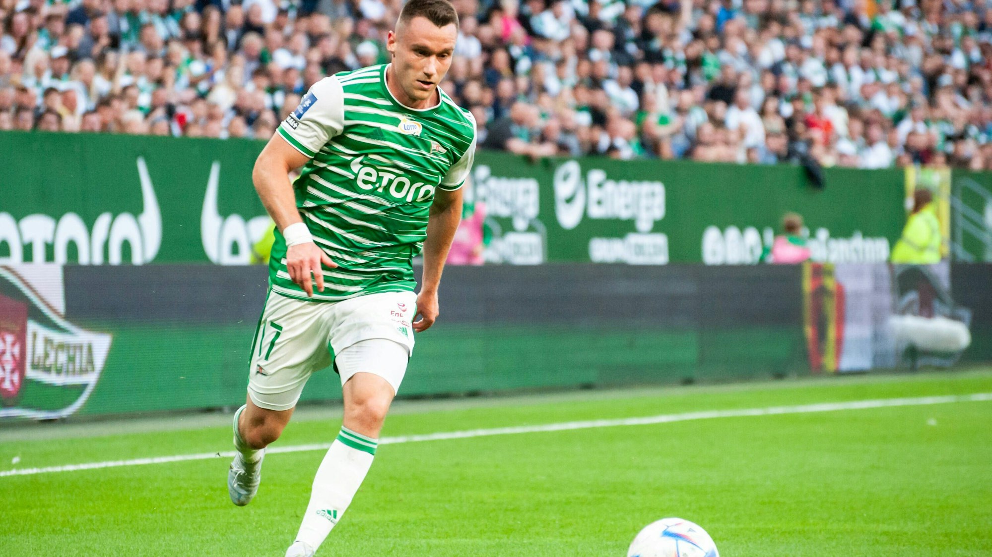 Ein Fußballspieler im grünen Trikot und weißer Hose läuft dem Ball hinterher.