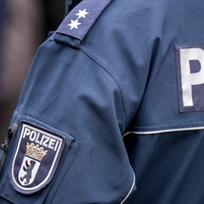 Die Aufschrift Polizei und der Wappen von Berlin auf der Uniform eines Polizeibeamten