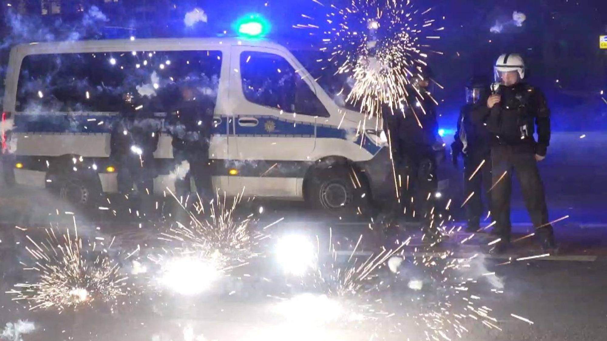 31.12.2022, Berlin: Polizeibeamte stehen hinter explodierendem Feuerwerk.