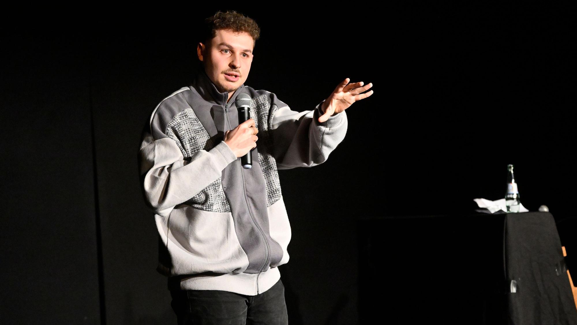 Fabian Lampert steht auf der Bühne vor dunklem Vorhang und referiert im Theas-Theater über Alkoholprobleme.