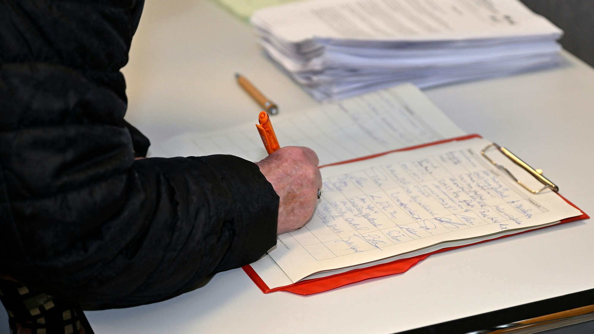 Jemand unterschreibt auf einer Liste.