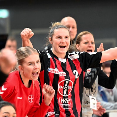 Eine Handballerin ballt neben ihre Mitspielerinnen die Fäuste zum Jubel.