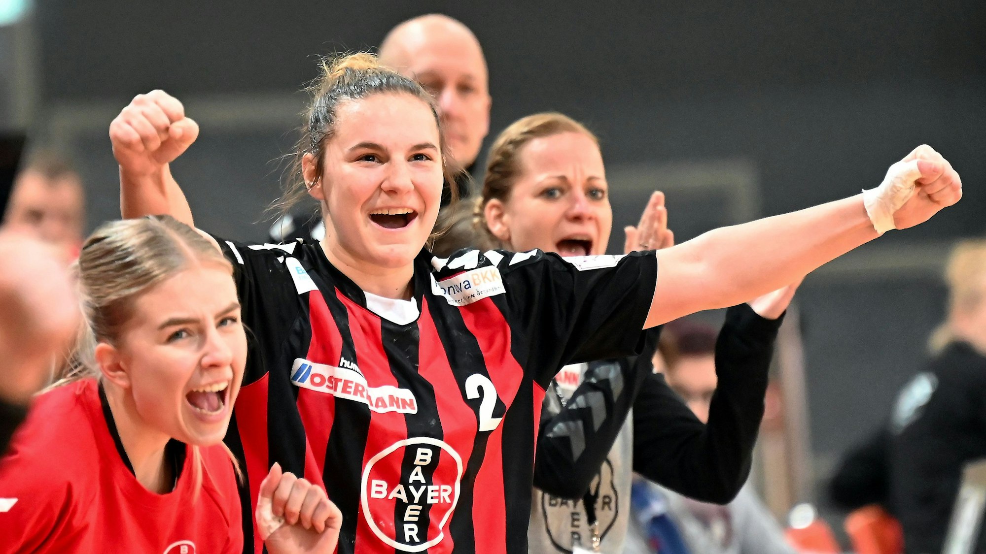 Eine Handballerin ballt neben ihre Mitspielerinnen die Fäuste zum Jubel.