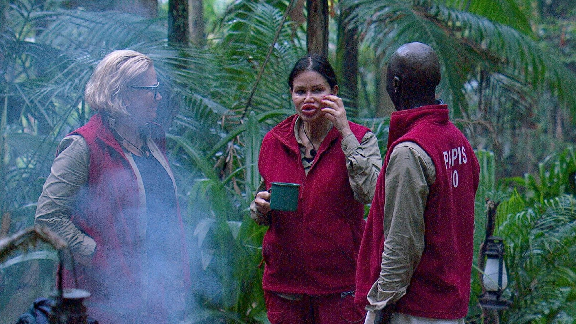 Claudia Effenberg, Djamila Rowe und Papis Loveday unterhalten sich im Camp.