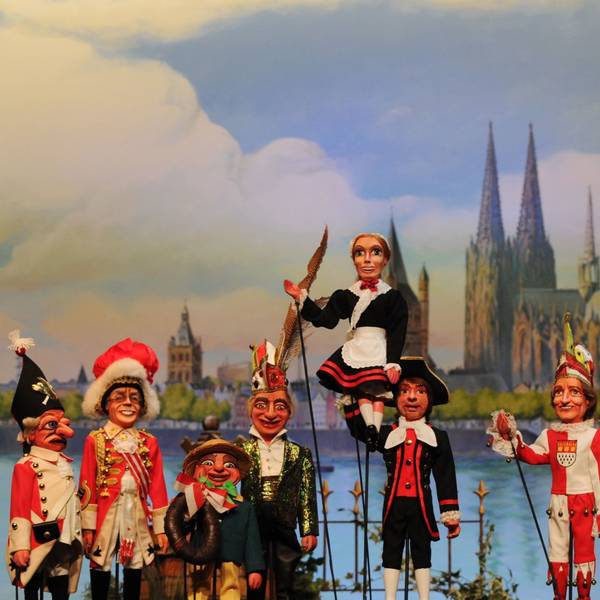 Stockpuppen des Hänneschentheaters vor dem Kölner Rheinpanorama: Rote Funken und Hellige Knäächte un Mägde posieren mit Speimanes und Sitzungsleiter Schäng.
