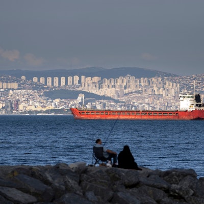 Im Hintergrund ist der Frachter zu sehen und im Vordergrund zwei Personen, die Angeln.