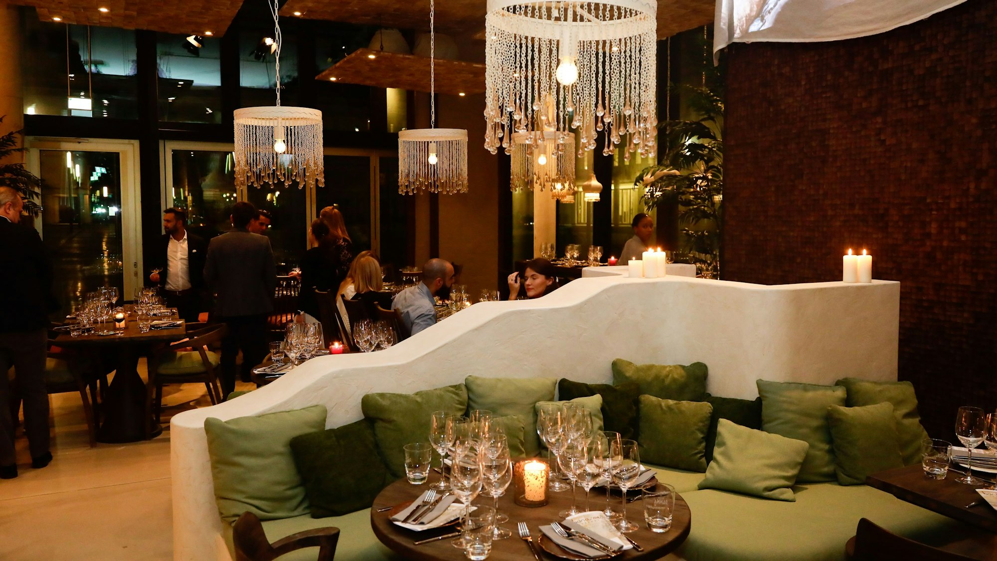 Das Restaurant bona'me im Kölner Gerling-Quartier von innen mit edlen Lampen, einer Sofa-Lounge und Menschen im Hintergrund.