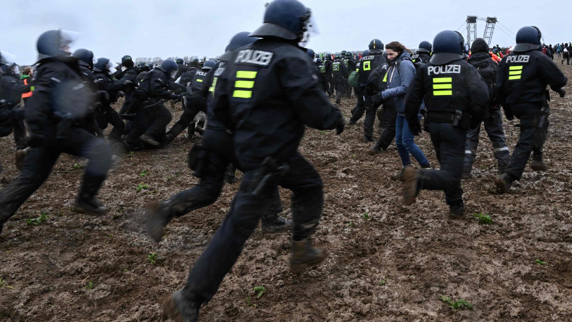 Lützerath am Samstag: Polizisten laufen durch den tiefen Schlamm.