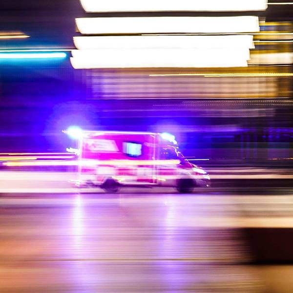 Ein Rettungsfahrzeug ist vor Tagesanbruch mit Blaulicht unterwegs (Aufnahme mit Mitzieheffekt).