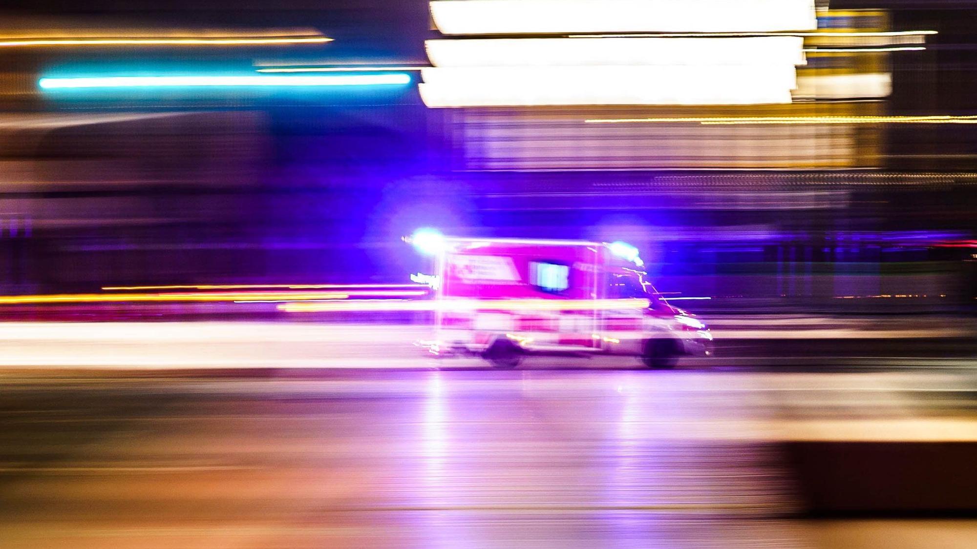 Ein Rettungsfahrzeug ist vor Tagesanbruch mit Blaulicht unterwegs (Aufnahme mit Mitzieheffekt).