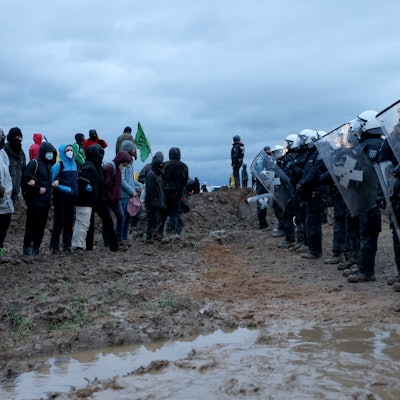Polizisten und Demonstranten stehen sich bei der Demonstration von Klimaaktivisten am Rande des Braunkohletagebaus bei Lützerath gegenüber.