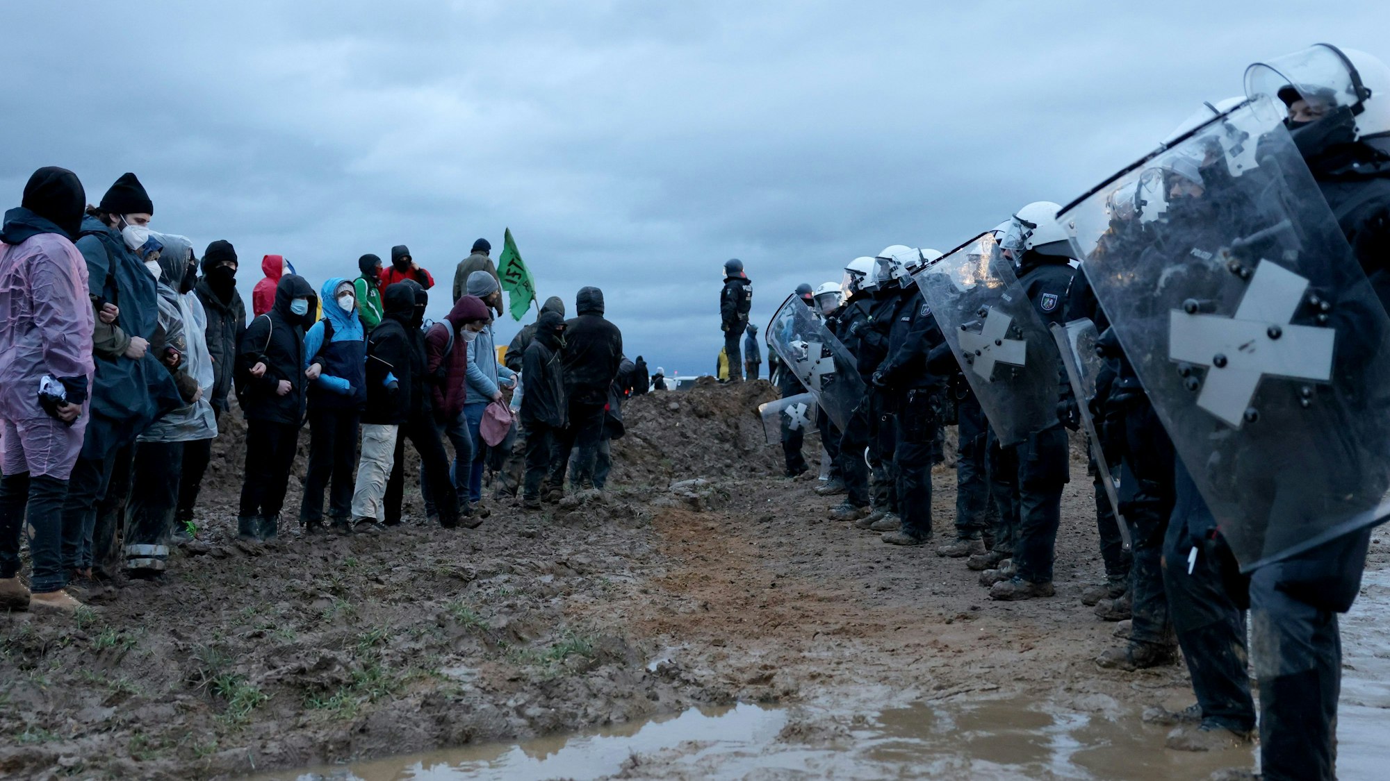 Polizisten und Demonstranten stehen sich bei der Demonstration von Klimaaktivisten am Rande des Braunkohletagebaus bei Lützerath gegenüber.