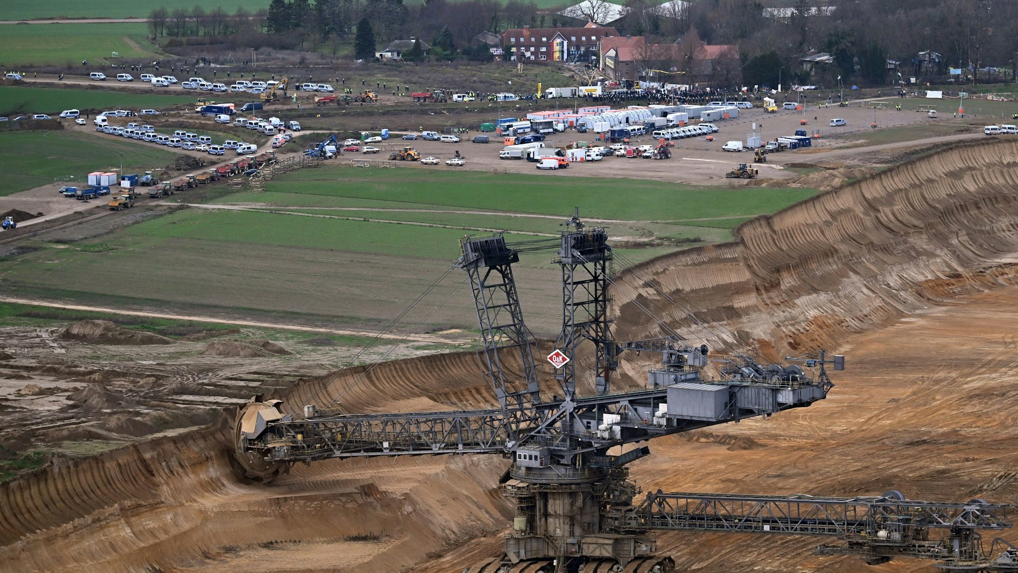 Polizeiautos und Polizisten stehen vor der Ortschaft Lützerath.
