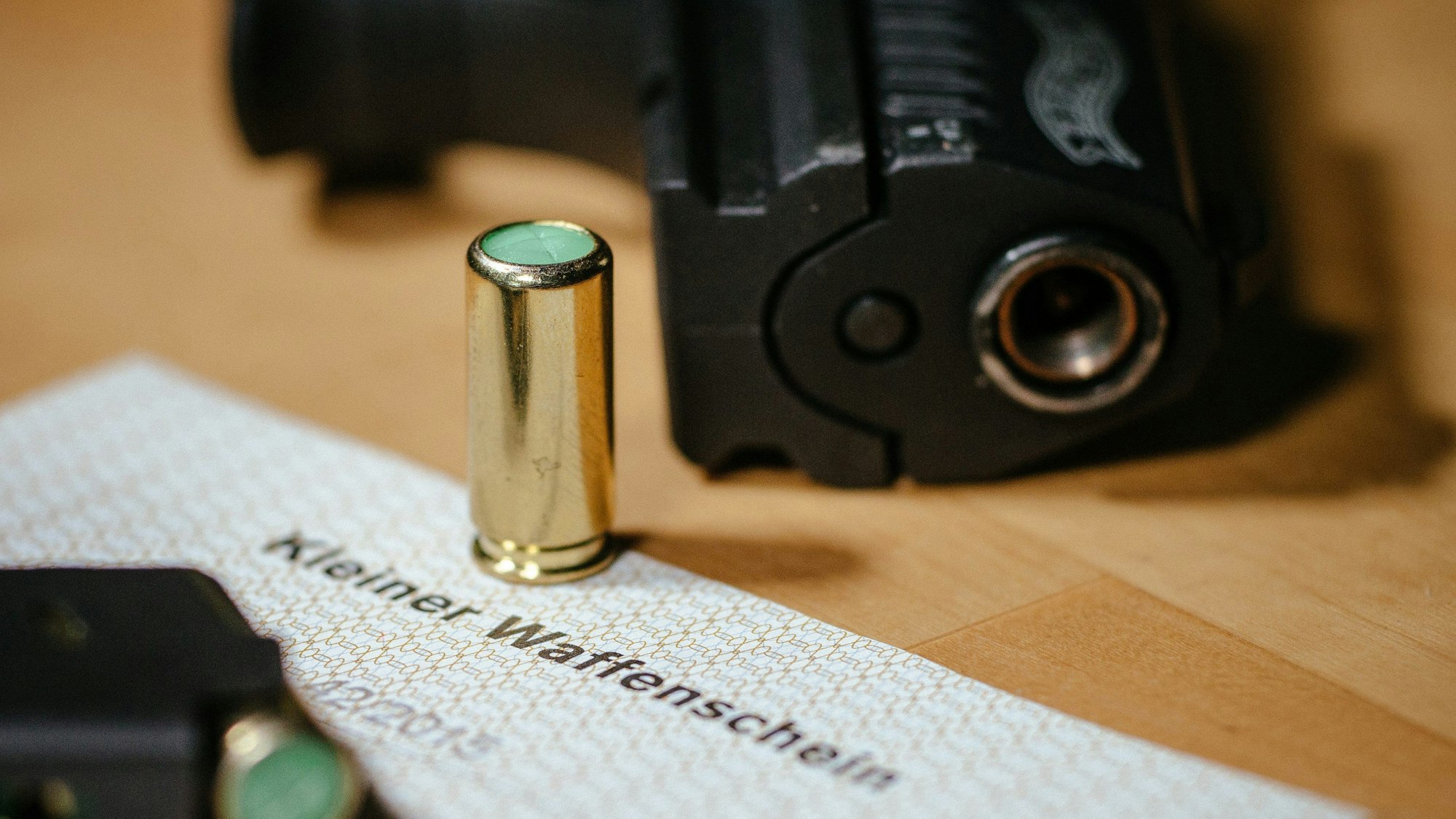 ARCHIV - 27.11.2015, Sachsen, Dresden: Ein kleiner Waffenschein liegt zwischen einer Schreckschuss-Pistole «Walther P22», einem Magazin und einer Platzpatrone. Er berechtigt zum Führen von Gas-, Signal- und Schreckschusswaffen. Die Zahl der kleinen Waffenscheine in Hamburg nähert sich der Zahl von 10 000. (zu dpa «Zahl der kleinen Waffenscheine in Hamburg weiter gestiegen») Foto: Oliver Killig/zb/dpa +++ dpa-Bildfunk +++