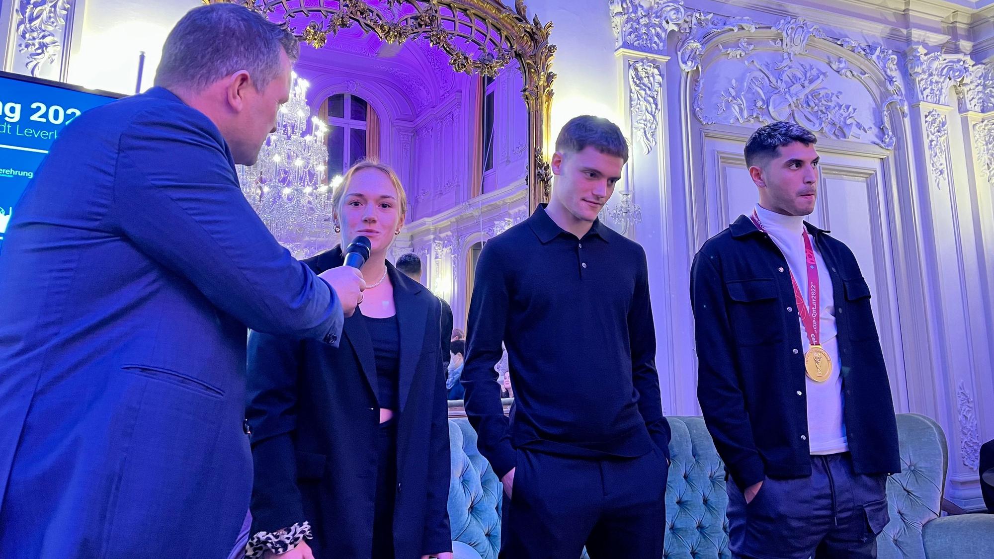 Lisanne Gräwe, Florian Wirtz und Exequiel Palacios stehen zu Interviews auf der Bühne