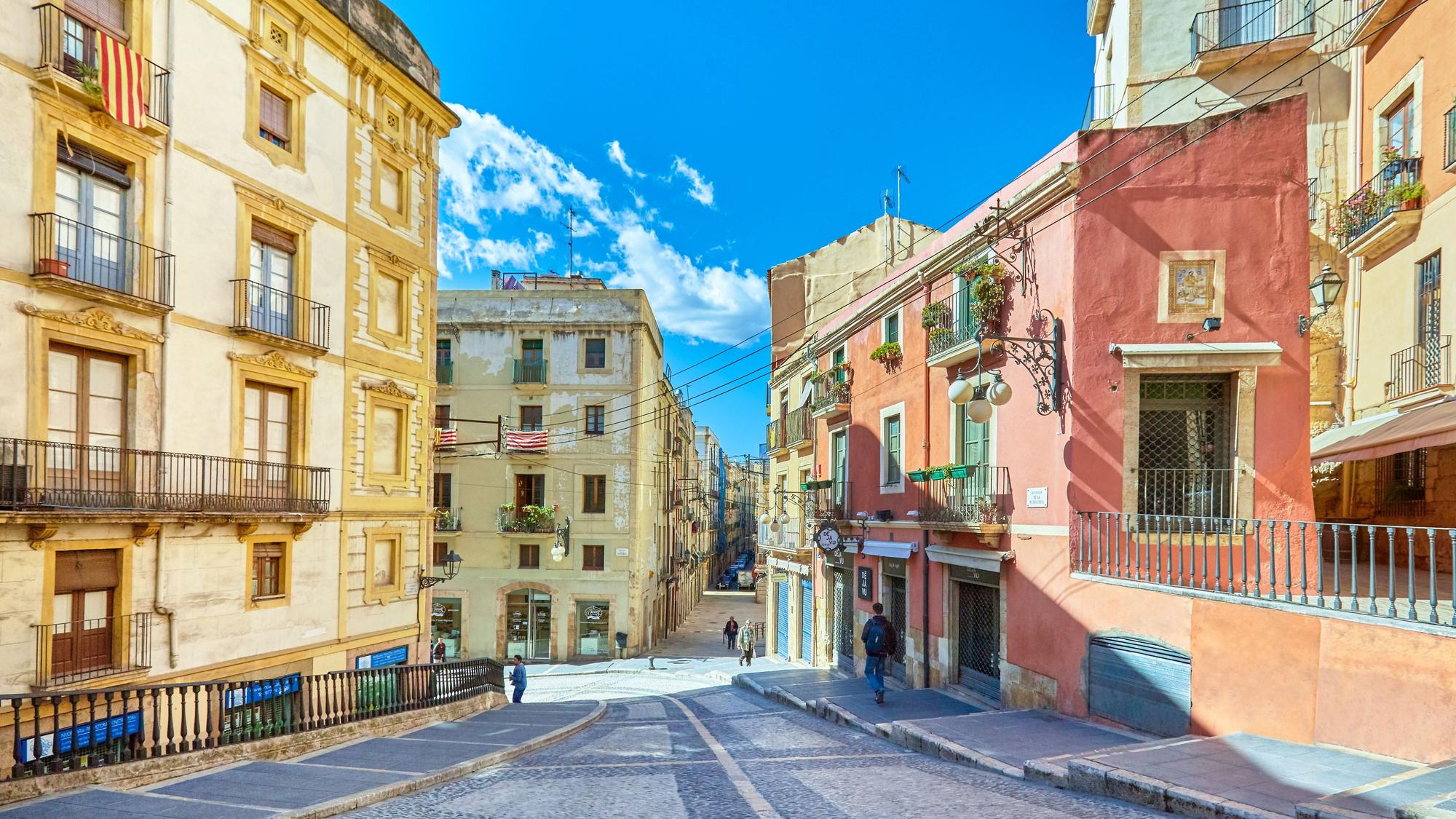 Eine abschüssige Straße in Tarragona mit alten Häusern in roten und gelben Tönen
