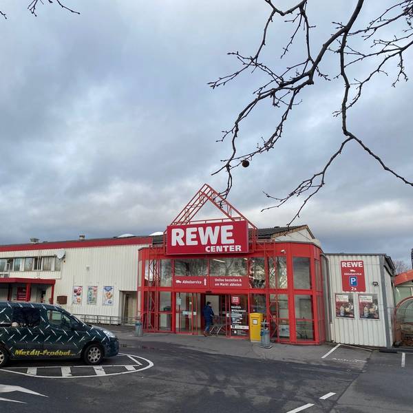 Vor dem Rewe-Center in Brühl-Ost parken Autos, ein Kunde schiebt seinen Einkaufswagen ins Geschäft.