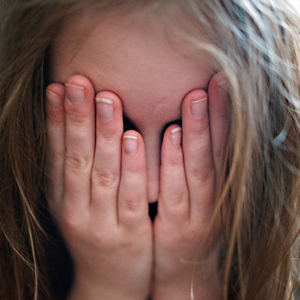 Ein Mädchen hält sich beide Hände vor das Gesicht.