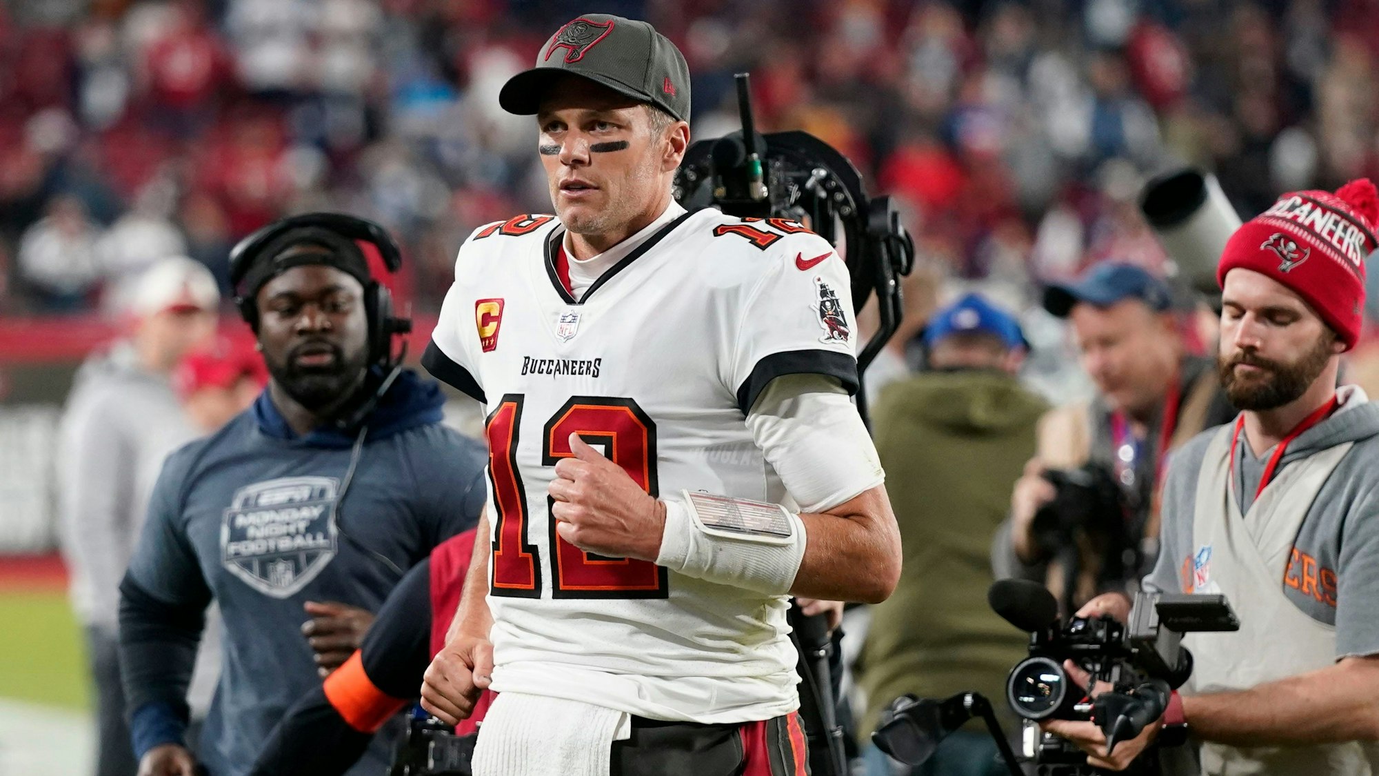 American-Football-Spieler Tom Brady steht auf dem Spielfeld. Er ist im Lauf und guckt ernst.