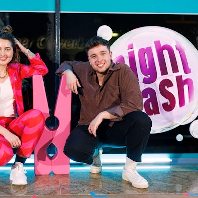 Luisa Charlotte Schulz und Ben Schafmeister hocken neben einer großen Wäscheklammer auf der Bühne vom Waschsalon, in dem Nightwash aufgezeichnet wird.