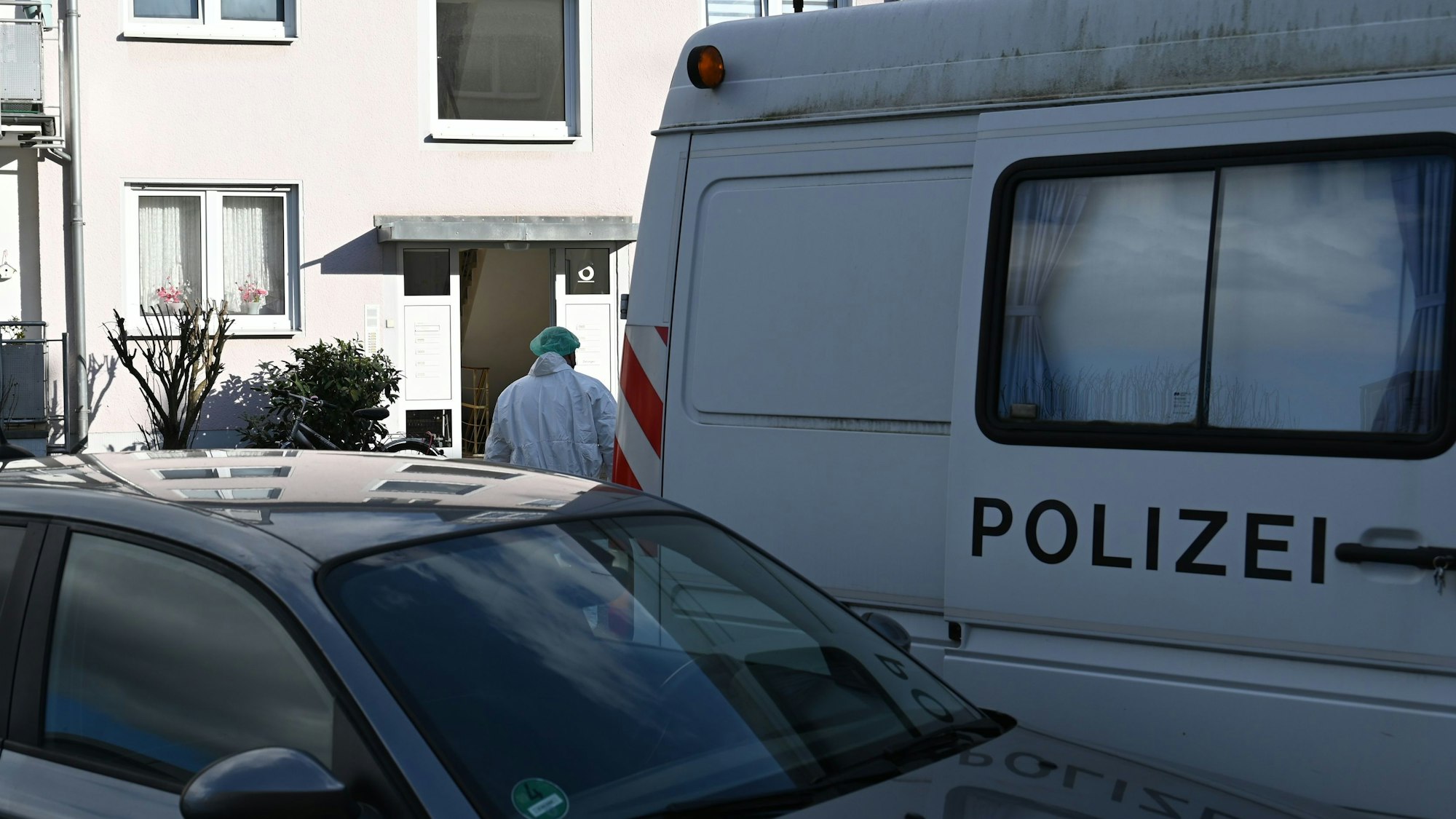 Ein Ermittler der Polizei in weißem Overall geht auf ein Haus in Kerpen zu.