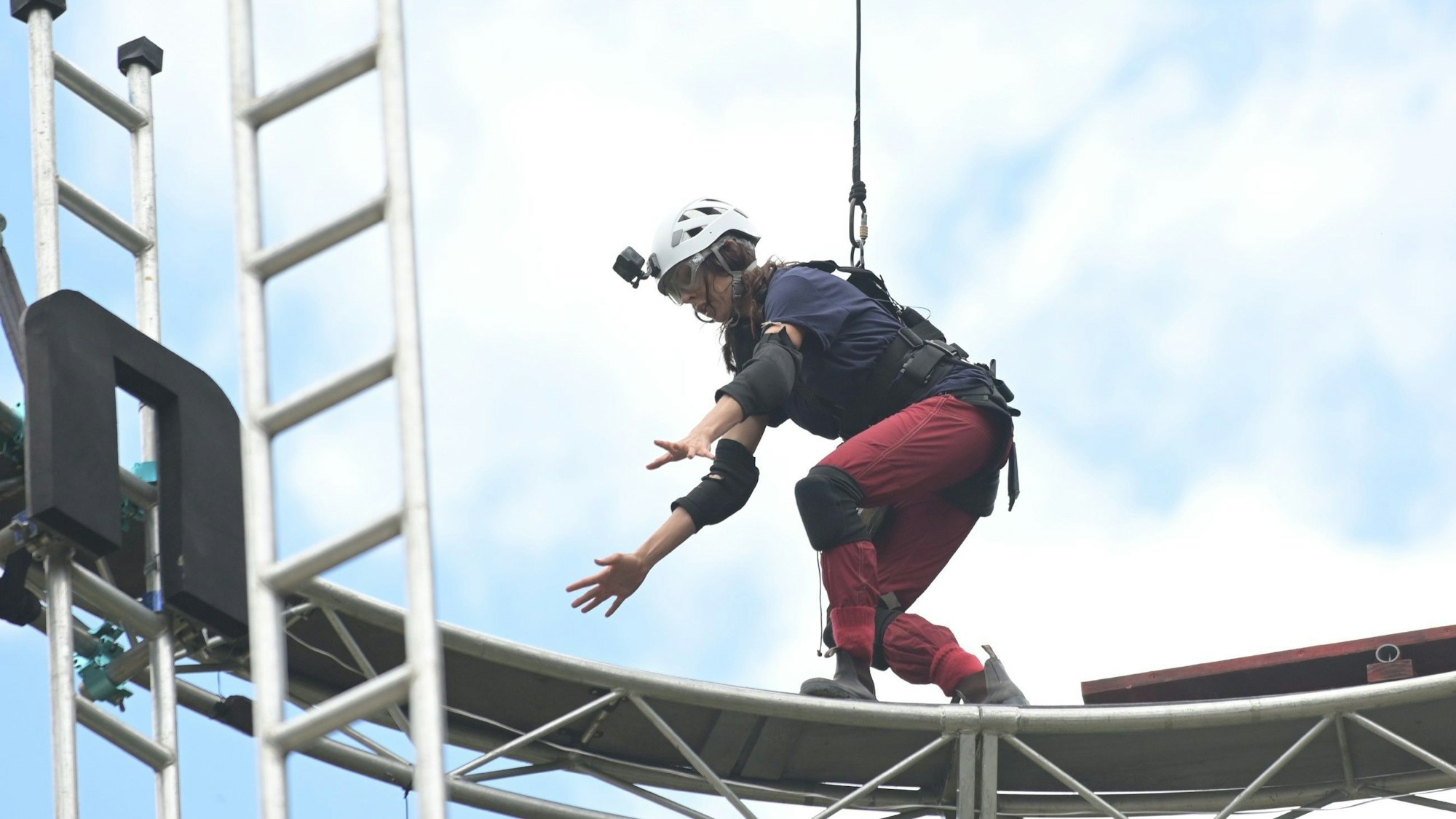 Es ist Jana zu sehen, wie sie auf dem Gerüst-Ring balanciert.