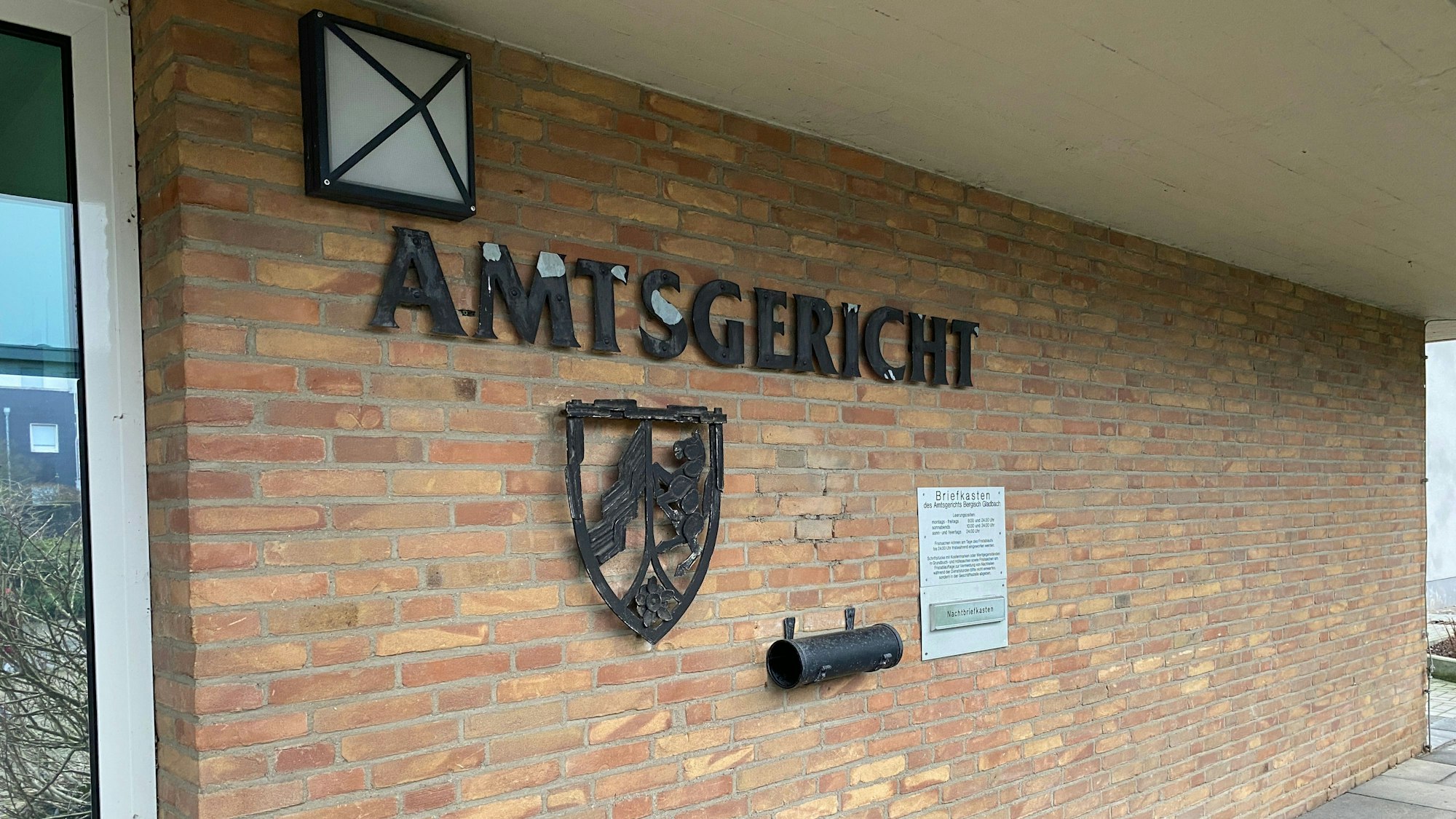 Eine Frau steht mit einem Telefon am Fenster, vor dem ein Stalker steht.