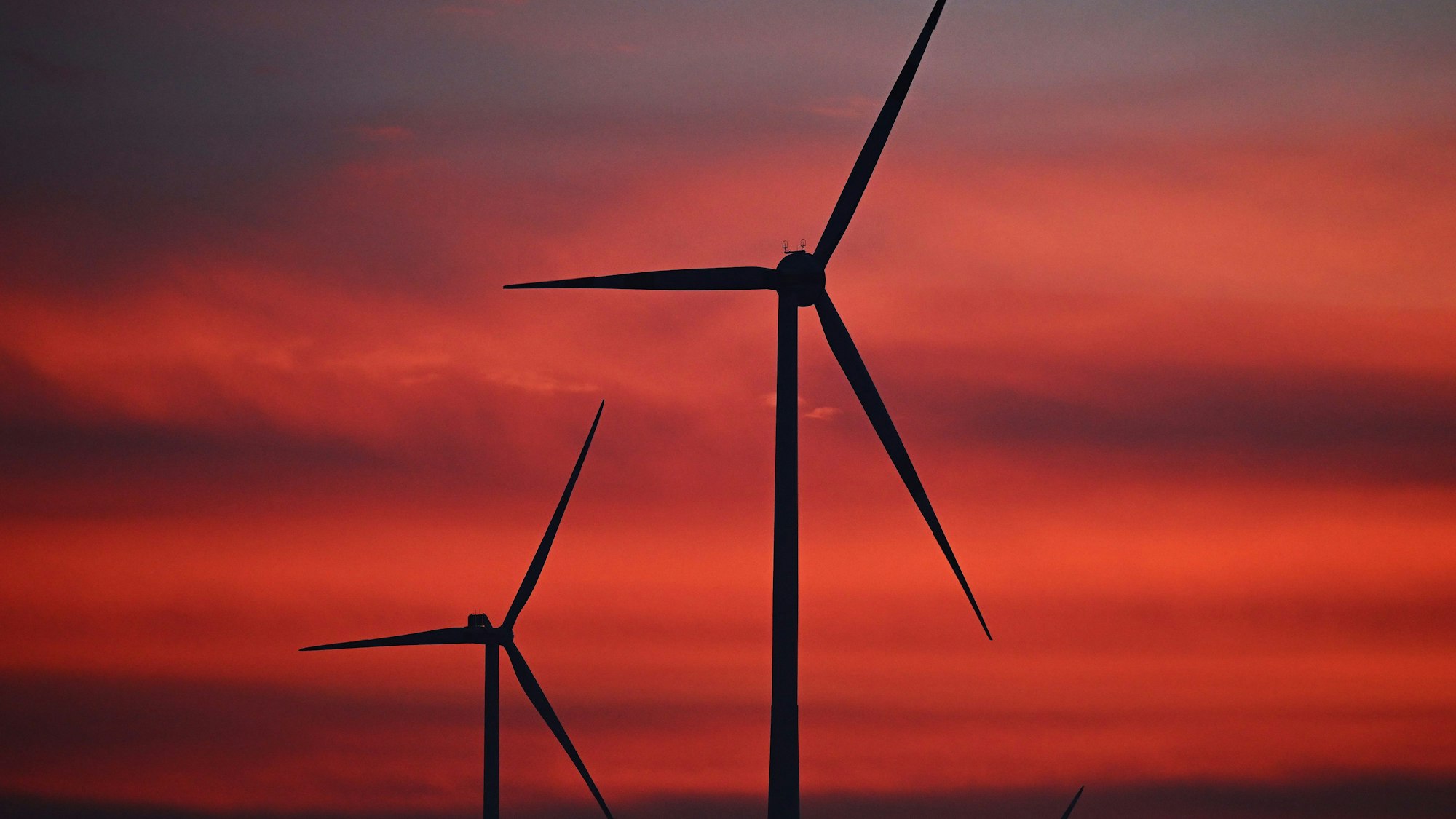 Windräder sind im Windpark Neudorf bei Sonnenaufgang zu sehen.