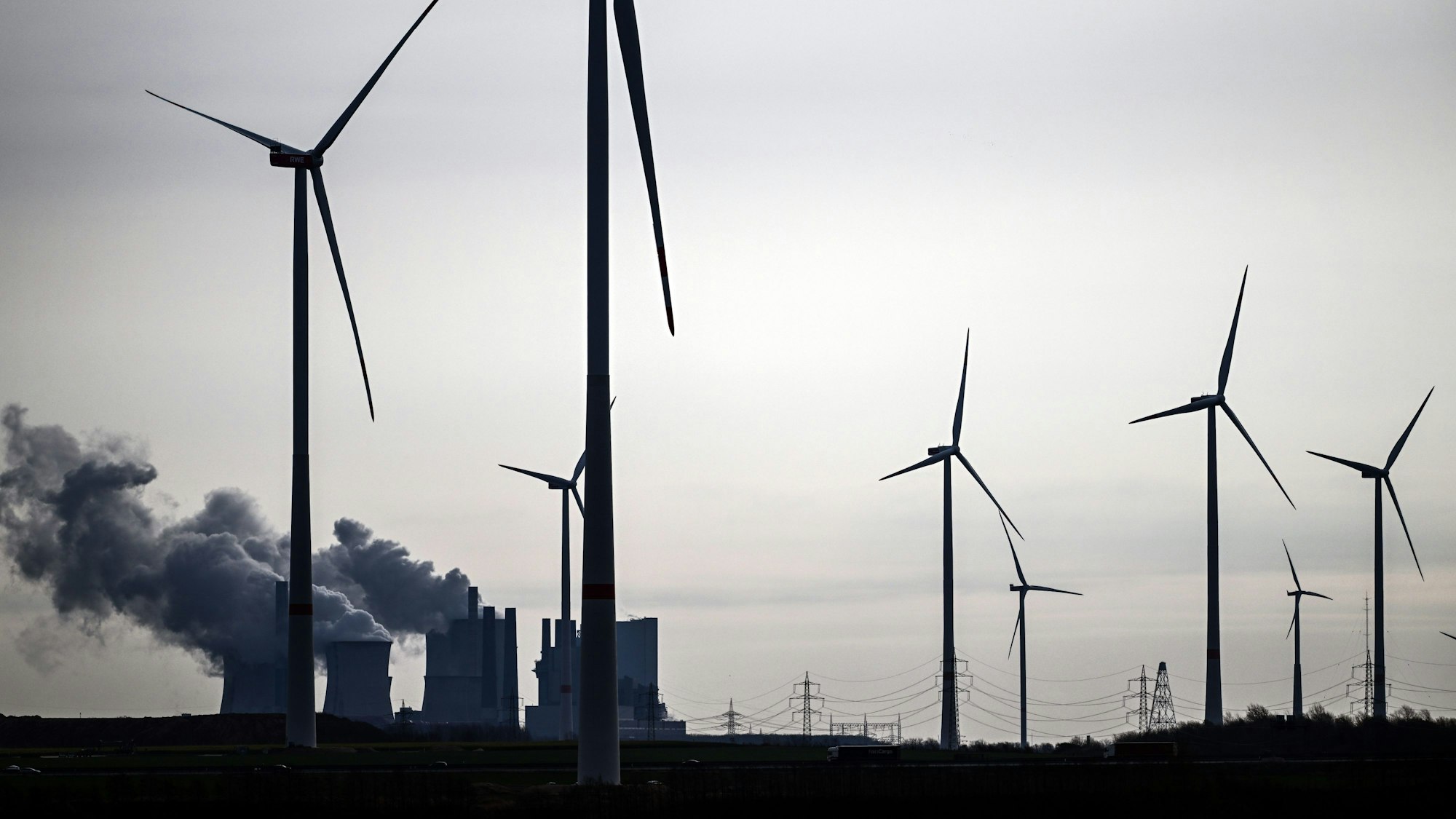 Jackerath: Windräder stehen am Braunkohletagebau Garzweiler, im Hintergrund ist das Braunkohlekraftwerk Neurath zu sehen mit seinen dampfenden Türmen.