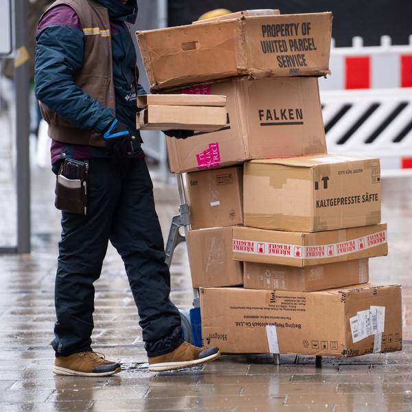 Ein Paketbote liefert in einer Stadt seine Pakete aus.
