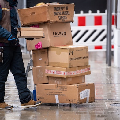 Ein Paketbote liefert in einer Stadt seine Pakete aus.