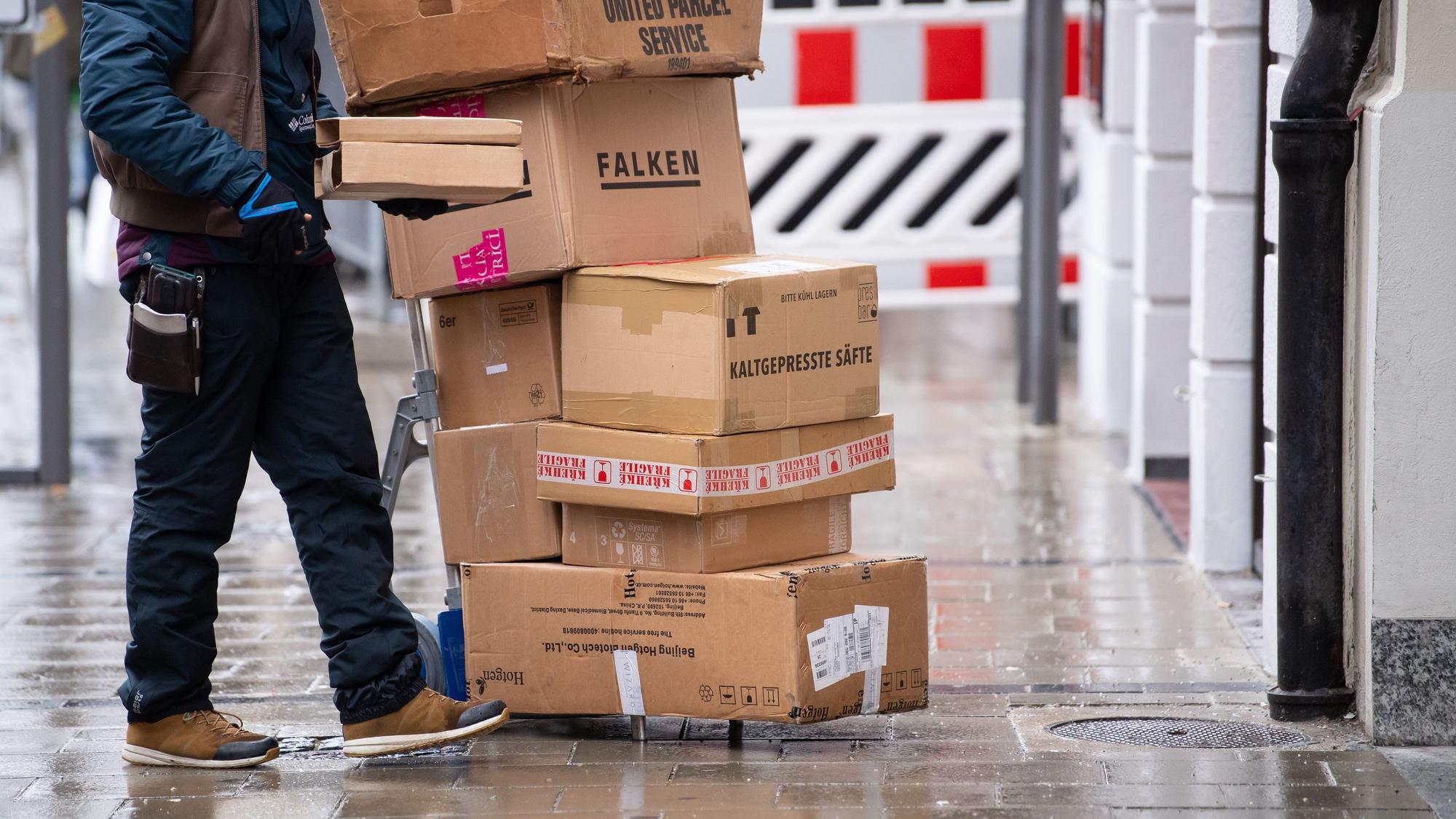 Ein Paketbote liefert in einer Stadt seine Pakete aus.