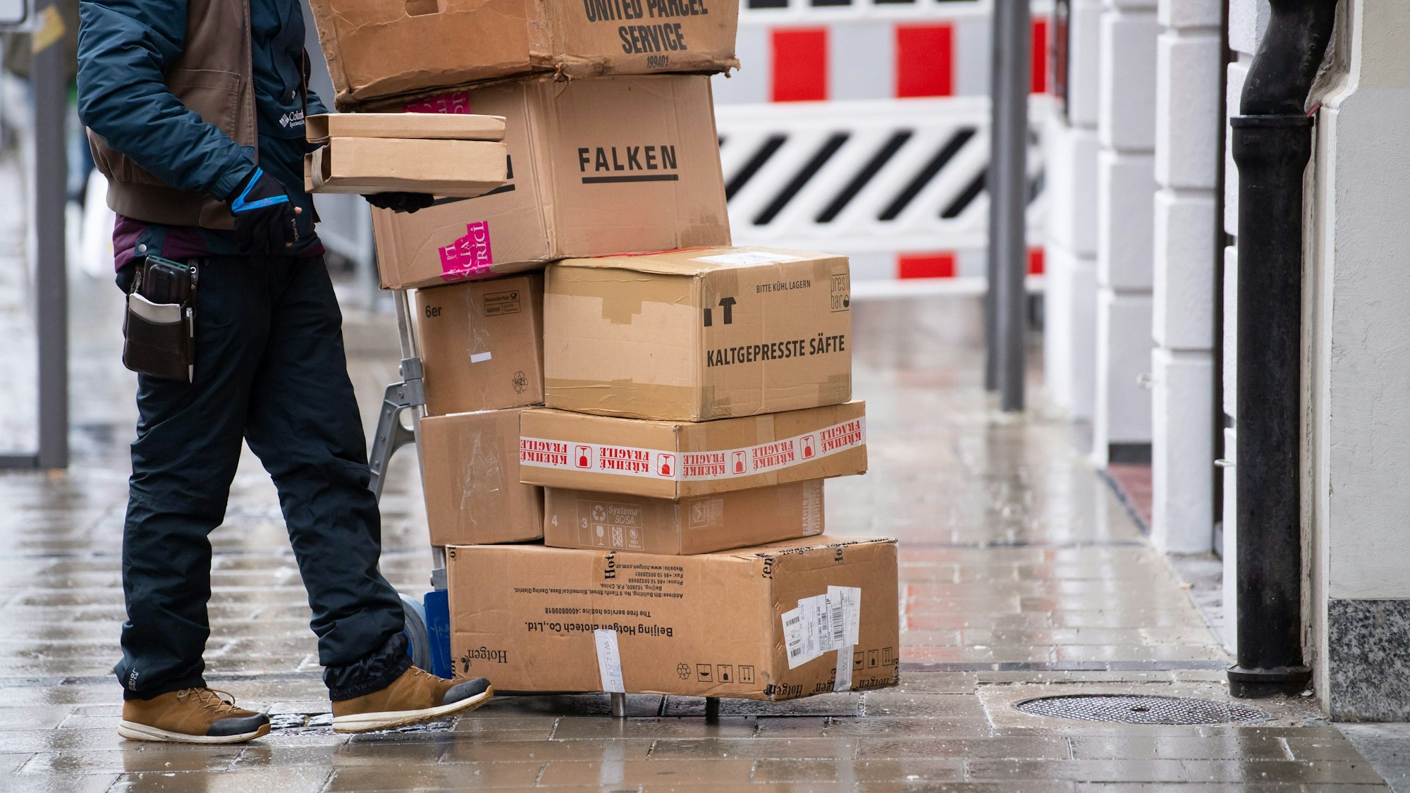 Ein Paketbote liefert in einer Stadt seine Pakete aus.