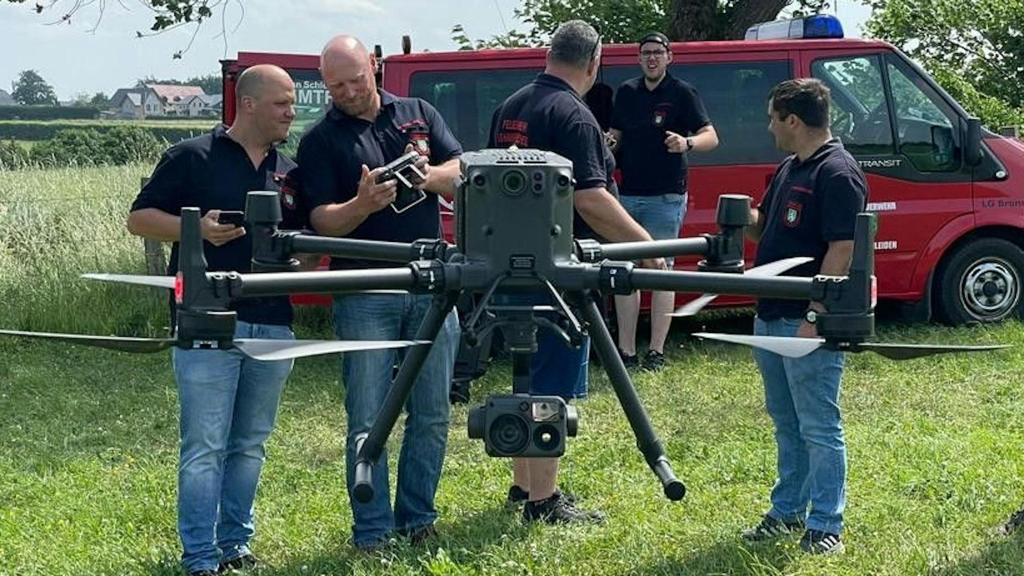 Eine Drohne der Feuerwehr ist gerade abgehoben. Im Hintergrund stehen einige Feuerwehrleute.
