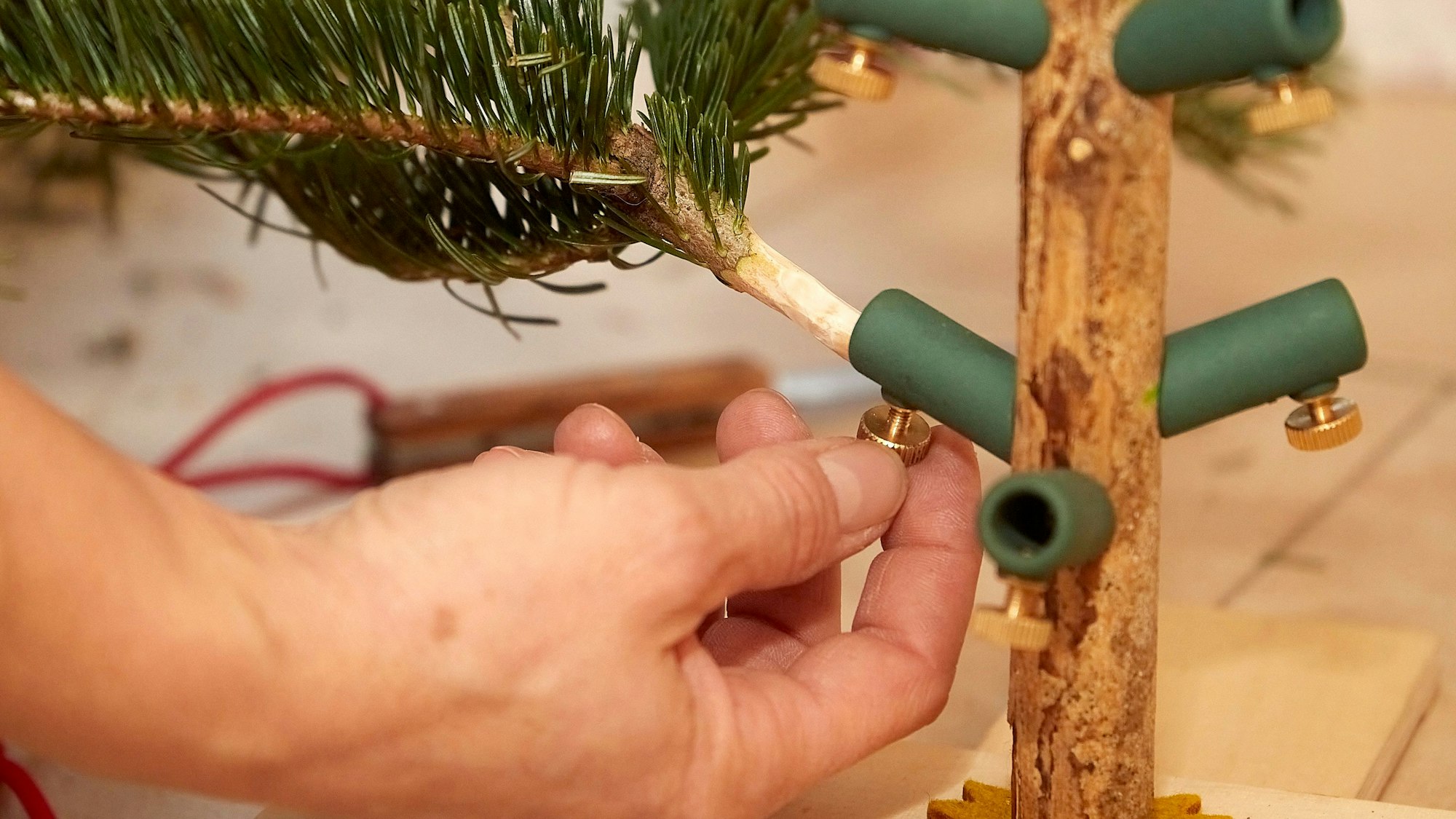 Ein Tannenzweig wird in einen Adapter gesteckt.