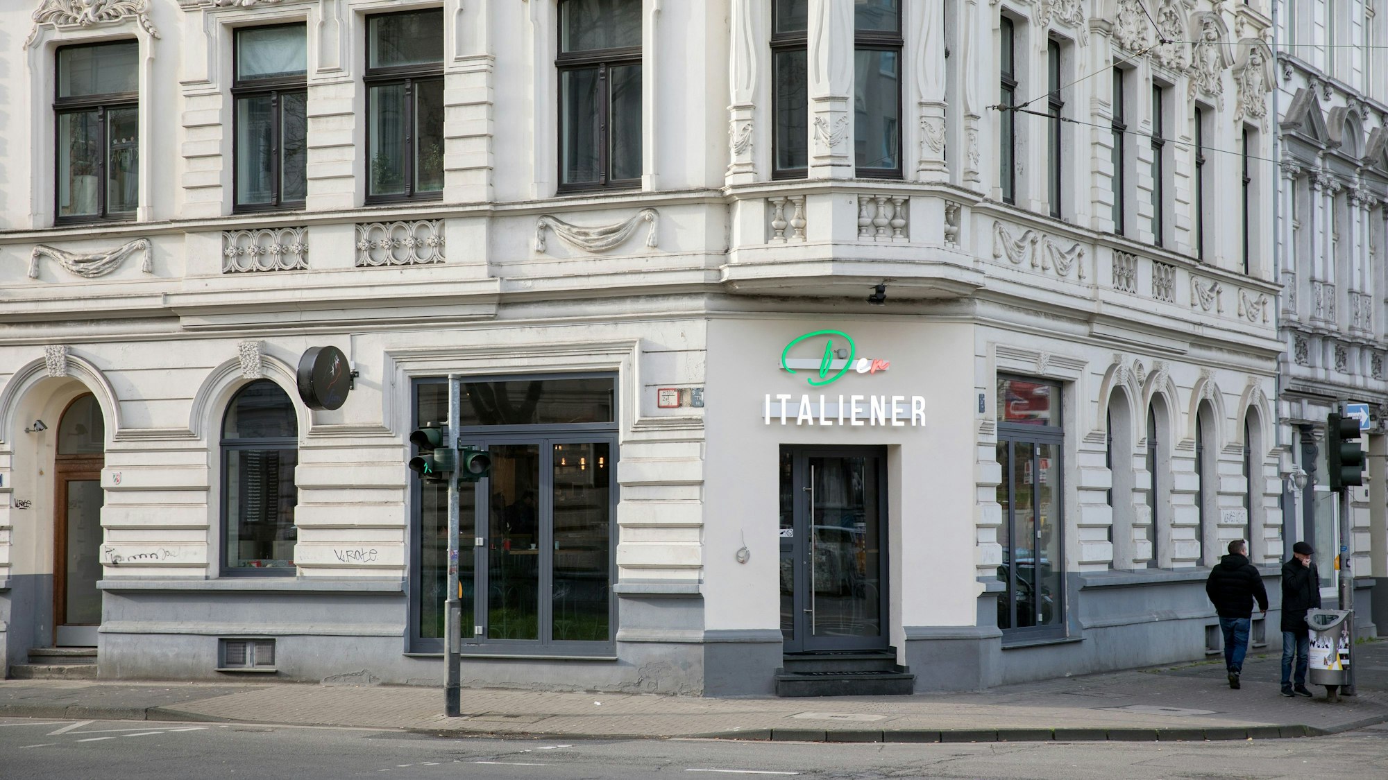 Das helle, stuckverzierte Gebäude mit dem Restaurant von außen. Über der Tür ist ein Neon-Schild angebracht.