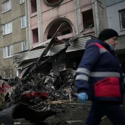 Arbeiter gehen an der Absturzstelle eines Hubschraubers auf zivile Infrastruktur in Brovary vorbei.
