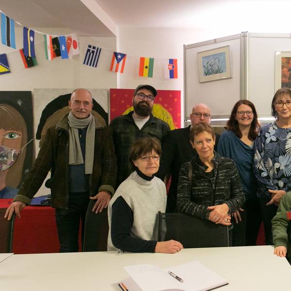 Eine Gruppen von Menschen eröffnet eine Kunstausstellung.