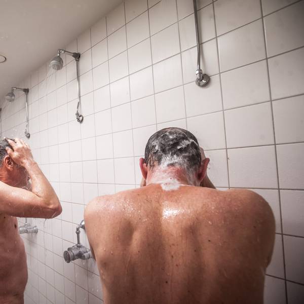 Zwei Männer stehen unter einer Gemeinschaftsdusche.