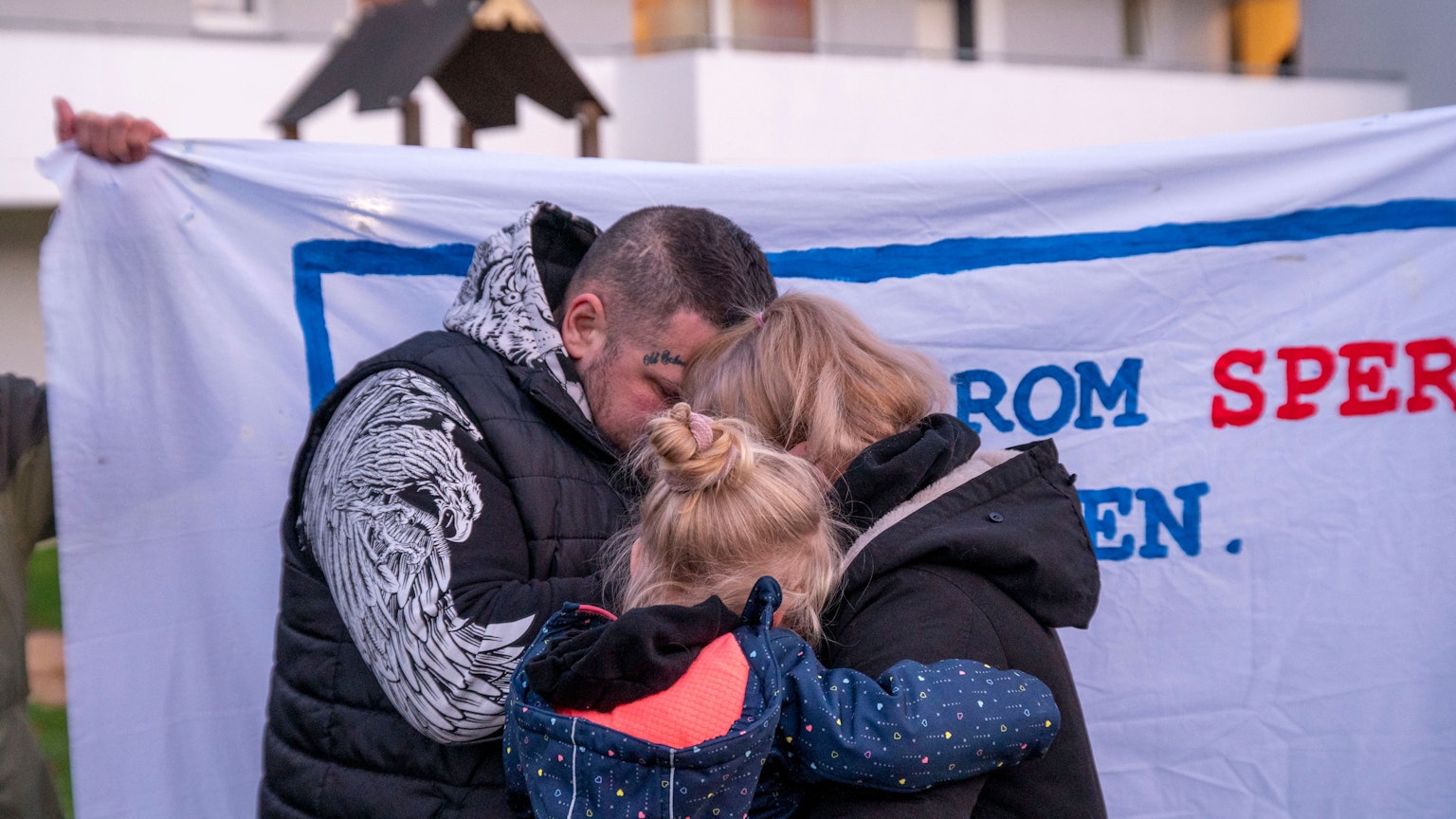 Protestkundgebung gegen Zwangsräumung von sechsköpfiger Familie in Gremberghoven: Vater, Mutter und ein Kind umarmen sich.