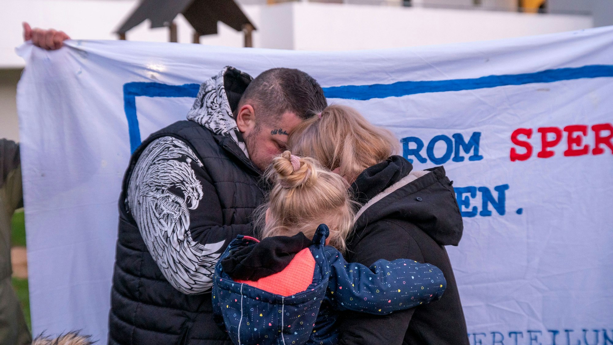 Protestkundgebung gegen Zwangsräumung von sechsköpfiger Familie in Gremberghoven: Vater, Mutter und ein Kind umarmen sich.
