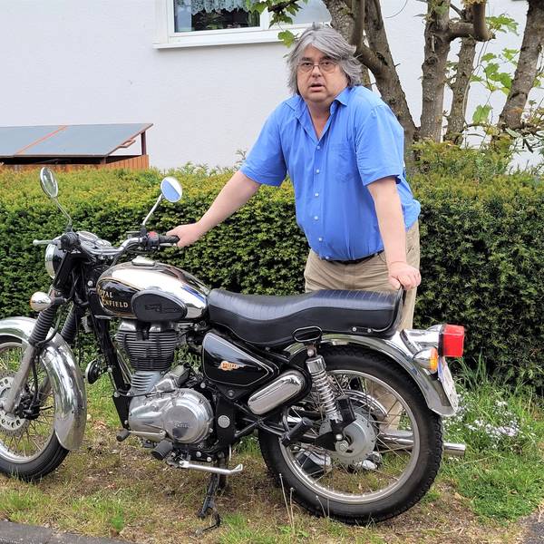 Ein Mann steht an einem Motorrad.