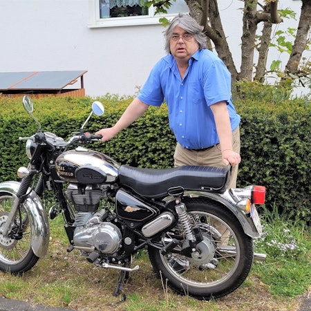 Ein Mann steht an einem Motorrad.