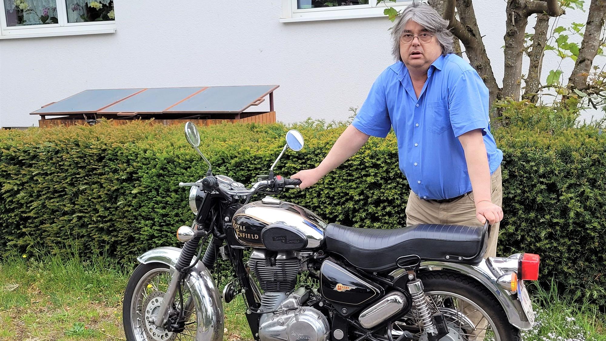 Ein Mann steht an einem Motorrad.